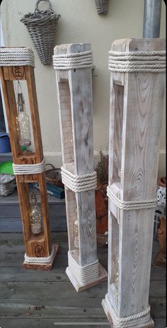 three tall wooden poles with rope on them sitting in front of a wall and potted planter