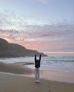 a person standing on the beach with their arms in the air