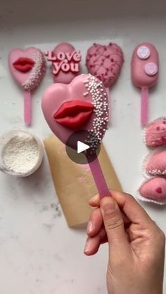 a person holding a pink lollipop in front of valentine's day decorations