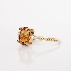 The Oval Citrine Sunrise ring features a natural orange oval citrine center stone. A ring to remind you of the beauty of a sunrise. Handcrafted in your choice of gold vermeil, or 14K solid gold. Also, comes with a diamond and moissanite center stone here. Gold vermeil or 14k solid gold 8x6mm natural oval Citrine Round CZs (what's this?) 1.2mm ring band ** This item is specially made for you. Please allow 1-2 week lead time. ShippingDomestic: Free standard shipping within the U.S.International: F Yellow Gold Citrine Oval Diamond Ring, Oval Citrine Diamond Ring In Yellow Gold, Oval Orange Topaz Ring With Center Stone, Orange Oval Topaz Rings, Oval Citrine Diamond Ring, Oval Citrine Diamond Promise Ring, Orange Oval Topaz Promise Ring, Oval Citrine Diamond Ring With Prong Setting, Oval Orange Topaz Promise Ring