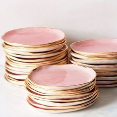 a stack of pink and gold plates on a white counter top with one plate in the middle