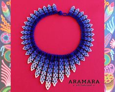 a blue and white beaded necklace on top of a pink card with the words aramara written below it