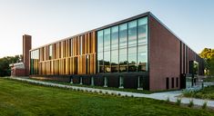 the building has many windows and is made of red brick with green grass on both sides