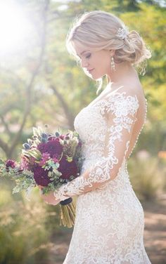 a woman in a wedding dress holding a bouquet of flowers with the sun shining behind her