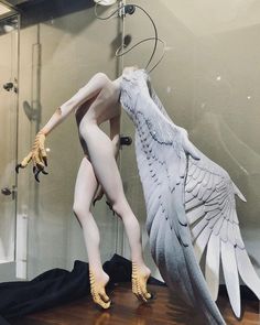 a mannequin with wings on display in front of a mirror