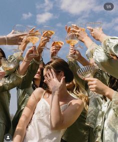 a group of women holding wine glasses in front of their faces with the sky behind them