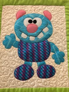 a blue teddy bear on a green quilt