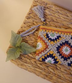 a woven purse sitting on top of a wicker basket next to a green plant