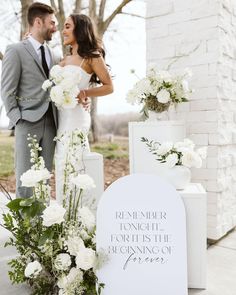 a bride and groom standing in front of a sign with flowers on it that says, remember tonight the forth is the beginning of forever