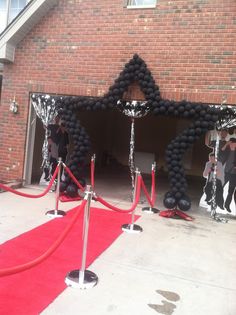 some black and white balloons are in front of a red carpeted entrance to a brick building