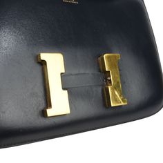 Hermes 'Constance 24' shoulder bag in dark navy leather with an adjustable shoulder strap, a back slip pocket, and a large gold 'H' clasp on the front. The bag has a top flap opening revealing a leather interior with a zip pocket. Includes dust bag. Brand = Hermes Size = 24 Condition = 7/10, Good. Light scratching in exterior leather particularly around closure, tarnishing and scratches to 'H' hardware, light scratching in lining. Material = Leather Hardware = Gold Dimensions = 9" x 6" x 2.5" Strap Drop = 23.5" (adjustable) SKU = 11258-45 Classic Rectangular Shoulder Bag With Metal Logo, Modern Rectangular Shoulder Bag With Metal Logo, Business Rectangular Shoulder Bag With Metal Logo, Designer Shoulder Bag With Metal Logo For Travel, Luxury Everyday Flap Bag With Metal Logo, Luxury Everyday Use Flap Bag With Metal Logo, Rectangular Office Shoulder Bag With Metal Logo, Gold Office Bags With Metal Logo, Business Crossbody Shoulder Bag With Metal Logo