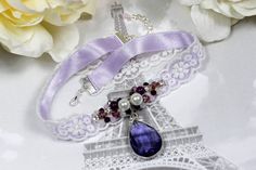 Lilac choker necklace with crystal pendant Made with light purple 1.5 cm wide satin ribbon and white floral lace trim, embroidered with diferrent size beads in pink, purple and white colours. the pendant is purple color teardrop shape glass bezel on a silver bail.  Full necklace length is 33 cm and it can be extended up to 38 cm, it has a lobster claw clasp in silver tone. Purple Choker Necklace For Gift, Purple Beaded Choker As A Gift, Elegant Purple Wedding Choker, Adjustable Purple Choker, Ribbon Choker Necklace For Weddings, Elegant Purple Choker Jewelry, Purple Choker For Party, Handmade Purple Choker For Party, Adjustable Purple Choker For Party