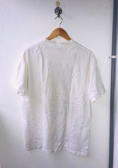 "Vintage" is a term that we don't take lightly. Our shops only feature tees that have been aged no less than 15 years.PLEASE ASK ANY QUESTION BEFORE BUYING!!! THIS IS USED CLOTHING!!! PLEASE DONT EXPECTED IT TO BE LIKE NEW OR IN PRISTINE CONDITION!!!PLEASE REFER TO THE ACTUAL/MANUAL SIZE TAKEN!!!Size  : LCondition : 8/10Made :USAColor :  White/  LogoMeasurement :armpit to armpit=21 "inchesLenght from top of the shoulder to bottom=27 "InchesIn a good vintage condition Vintage but still good and n Vintage Tops With Letter Print And Relaxed Fit, Vintage Relaxed Fit Top With Letter Print, Nostalgic Cotton Tops With Letter Print, 90s Style Crew Neck Cotton Shirt, Vintage Cotton Shirt With Crew Neck, Vintage Cotton Crew Neck Shirt, Vintage Cotton Shirt With Letter Print, Vintage Cotton Shirt With Graphic Print, Vintage Short Sleeve Tops With Text Print