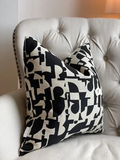 a black and white pillow sitting on top of a chair next to a light bulb