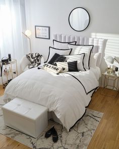 a white bed with black trim and pillows