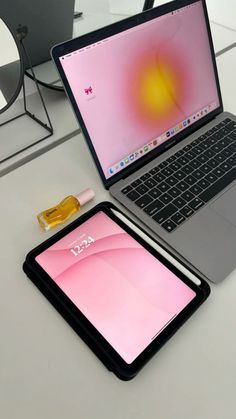 an open laptop computer sitting on top of a white table next to a cell phone