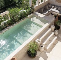 an outdoor swimming pool surrounded by plants and potted plants on either side of it