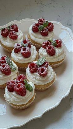 small cupcakes with whipped cream and raspberries