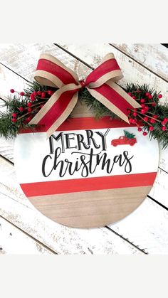 a merry christmas sign hanging on the side of a wooden wall with red and white ribbon