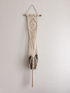 a macrame hanging on the wall next to a potted plant