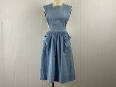 Vintage 1930s Pinafore dress. Made of blue chambray cotton. Vintage workwear or play wear. Two pockets. Back buttons with open sides. Has blue line selvedge inside. Made to be worn with a blouse underneath. About a size small. Actual measurements are:   25" around the waist   48" hips  17" shoulder to shoulder  43" overall length  In very good condition with a fade spot below left pocket, see picture. 1950s Cotton Vintage Dress For Daywear, Vintage Blue Dresses With Pockets, Blue Vintage Dresses With Pockets, Vintage Cotton Dresses For Work, Vintage Cotton Workwear Dresses, Fitted Cotton Pinafore Dress For Work, 1950s Style Blue Cotton Vintage Dress, Vintage Cotton Pinafore Dress With Pockets, Vintage Fitted Pinafore Dress For Spring