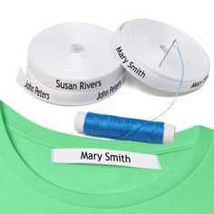 two t - shirts with name tags on them next to a thread and sewing needles