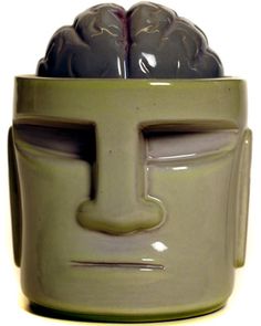 a green ceramic cup with a face on it