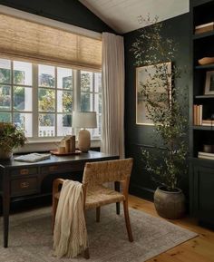 a home office with dark green walls and wood flooring, along with a large window