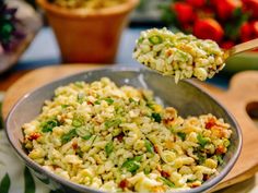 a bowl filled with macaroni salad on top of a wooden cutting board