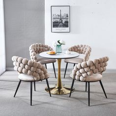 a table with four chairs around it and a vase on the table next to it