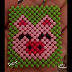 someone is holding a bead art piece in their hand and it looks like they are smiling