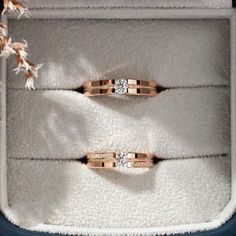 two wedding rings sitting in a box on top of a white carpeted floor next to each other