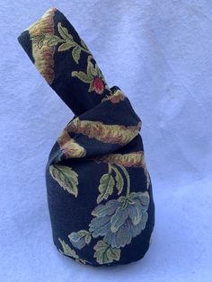 a neck tie with flowers on it sitting on a white surface in front of a blue background