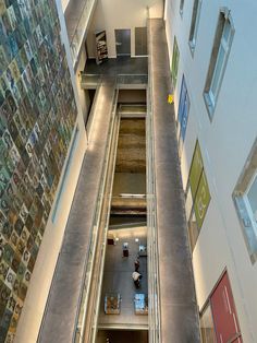 an escalator in a building with pictures on the wall and below it is a staircase