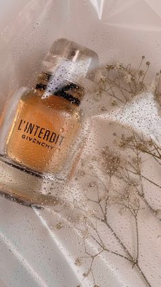 a bottle of perfume sitting on top of a window sill covered in raindrops