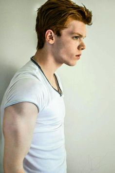 a man with red hair wearing a white t - shirt and looking off to the side