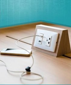 an electrical outlet plugged in to a phone charger on a wooden table with a blue wall behind it