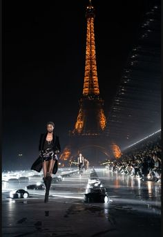 a model walks down the runway in front of the eiffel tower at night