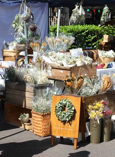 an assortment of flowers and wreaths for sale at a farmer's market stall