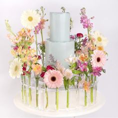 a white cake with flowers on it sitting on top of a table in front of a white wall