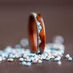 a wooden ring sitting on top of a pile of white and blue pebbles next to it