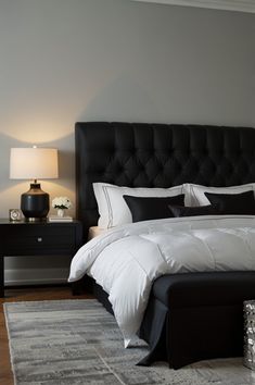 a black and white bed in a bedroom next to a nightstand with a lamp on it