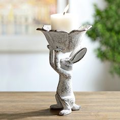 a candle holder with a rabbit holding a flower pot