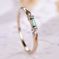 a close up view of a ring with an emerald stone and three diamonds on it