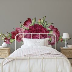 a white bed with pink flowers on the headboard and pillows in front of it