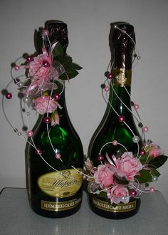 two wine bottles decorated with pink flowers and pearls