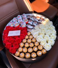 a tray filled with lots of chocolates and roses on top of a car seat