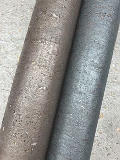 two rolls of metallic foil sitting next to each other on the cement floor with dirt all over them