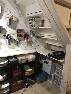 a kitchen area with shelves and drawers under the stairs