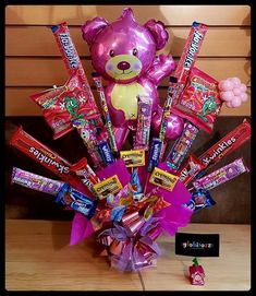 a pink teddy bear sitting on top of a table filled with candy